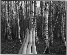 two women are laying on their backs in the woods, one is holding her head up