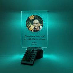 a remote control sitting on top of a table next to a glass plaque with an image of a woman