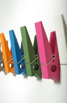 a row of colorful birdhouses hanging on a wall next to a string with holes in them