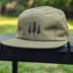 🌲🌲 5% of profits donated to preservation 🌲🌲  Gear up for your next adventure with our olive green tree 5 panel hat, the ultimate camp hat! Crafted from 100% cotton, this hat's flat bill keeps you cool and shaded as you conquer trails, lounge by the campfire, or explore the great outdoors. Your new adventure-ready essential! This hat is olive green with black embroidered trees on the front. Embroidery is custom designed by the shop owner, Alyssa, stitched on front. - 100% cotton - 5 Panel, Camp Hat - Head circumference: 19⅝″-22½″ - Flat Bill - Nylon adjustable strap - Custom embroidery, on the front center - Hand wash, dry flat - Olive green hat - The perfect hiking gift, camping gift and nature gift! Embroidered Trees, Olive Green Hat, Camper Hat, Camp Hat, Five Panel Hat, Hiking Hat, Flat Brim Hat, 5 Panel Hat, Hiking Gifts