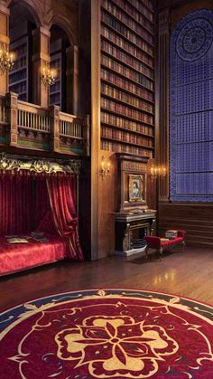 an ornate library with red velvet curtains and chandelier, bookshelves, and rug