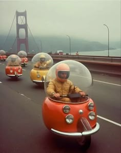 two people in small cars driving on the road with bridge in back ground and foggy sky behind them