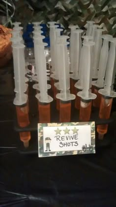 several bottles filled with liquid sitting on top of a black table covered in plastic cups