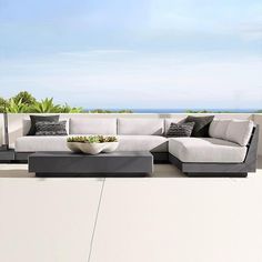 a large sectional couch sitting on top of a white floor next to a planter