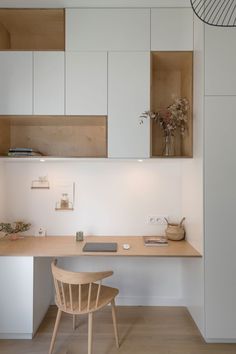 a desk and chair in a room with white walls, wooden floors and open shelving