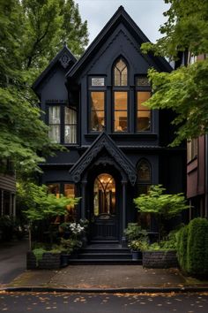 a black house with lots of windows and trees in the front yard is lit up at night