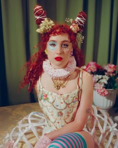 a woman with red hair sitting on top of a table