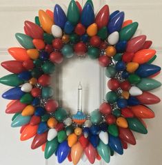 a wreath made out of colorful glass beads on a wooden fence with no people around it