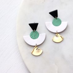 two tone earrings with black, white and green accents on a marble slab topper