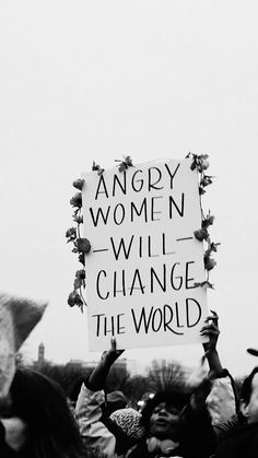 many people are holding up signs and hats in the air while one person holds a sign that says, angry women will change the world