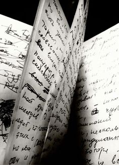 an open book with writing on the pages is shown in this black and white photo