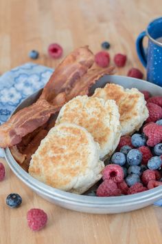 a bowl filled with breakfast foods on top of a wooden table next to a cup of coffee