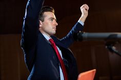 a man in a suit and tie raising his fist