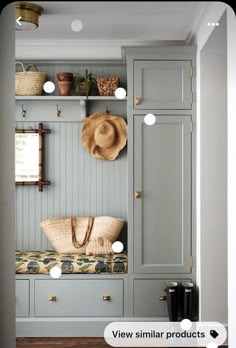 an entryway with gray cabinets and hats on the shelves, along with a bench