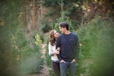 a man and woman standing next to each other in the woods