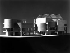 black and white photo of an architectural building with multiple levels on the roof, in front of a dark sky