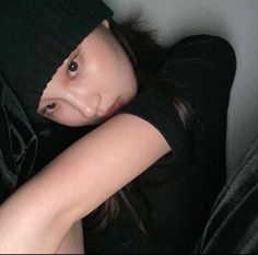 a young woman wearing a black shirt and beanie is posing for the camera with her arms behind her head