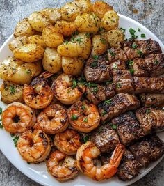 steak, shrimp and potatoes on a white plate with garnished skewers