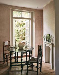 a table and chairs in front of a window with an open fire place next to it