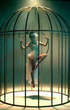 a woman is in a cage with a hoop around her neck and heels on the floor