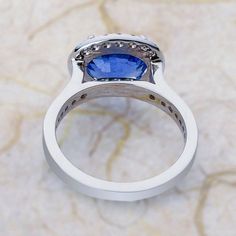 a white gold ring with a blue sapphire and diamond set in the shants, on a marble background