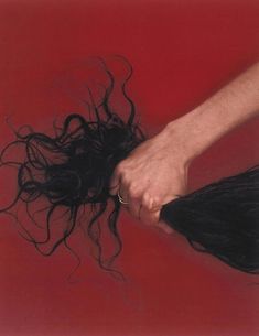 a woman's long hair is being blown by the wind on a red background