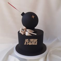 there is a black cake with a gold bow on top and a snowman made out of it