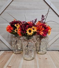 three jars with flowers in them sitting on a table