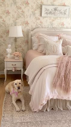 a dog sitting on the floor in front of a bed with pink and white decor