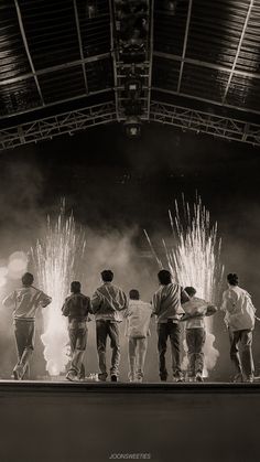 a group of people standing on top of a stage with fireworks in the sky behind them