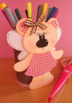 a teddy bear with pencils and scissors in it's holder on a table