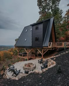 a small cabin on top of a mountain with a fire pit in the foreground