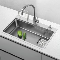 a stainless steel kitchen sink with two green vegetables