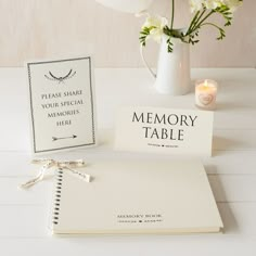 a table with a book, candle and flowers on it next to a card that says memory table