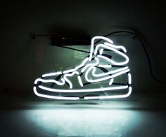 a neon sign with a pair of shoes on it's side in the dark