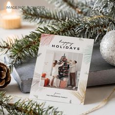 a christmas card sitting on top of a box next to a pine cone and candle