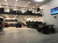 an indoor garage with two atvs and a boat on the wall, in front of a flat screen tv