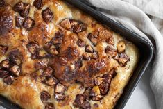 a casserole dish with cheese and nuts in it on a white table cloth