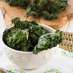 a white bowl filled with greens on top of a table