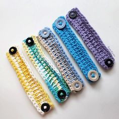 four crocheted hair clips are lined up on a white surface with black buttons