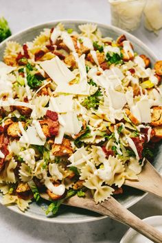 a bowl filled with pasta and meat covered in parmesan cheese next to two wooden spoons