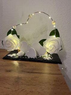 some white roses are sitting on a table with lights in the shape of hearts and eggs