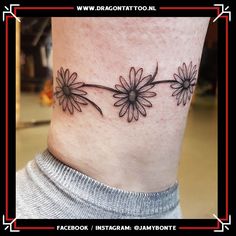 a black and white photo of a woman's ankle with daisies on it