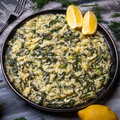 a bowl filled with rice and greens next to lemons