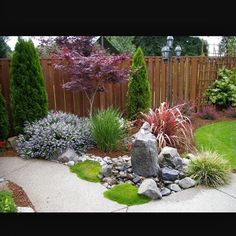 a small garden with rocks and plants in the foreground, surrounded by a wooden fence