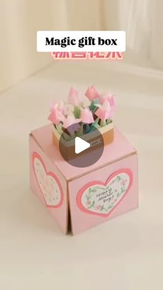 a pink box with flowers in it on top of a white surface and the words magic gift box written below