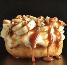 a pastry covered in caramel and bananas on a black surface with sauce drizzled over it