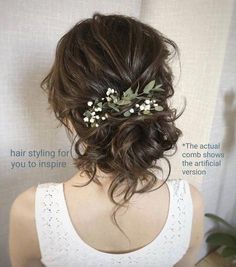 the back of a woman's head wearing a white top with flowers in her hair