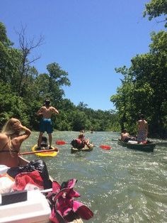 several people are on rafts in the middle of a river while others paddle down it