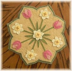 a close up of a doily on a wooden table with white and pink flowers